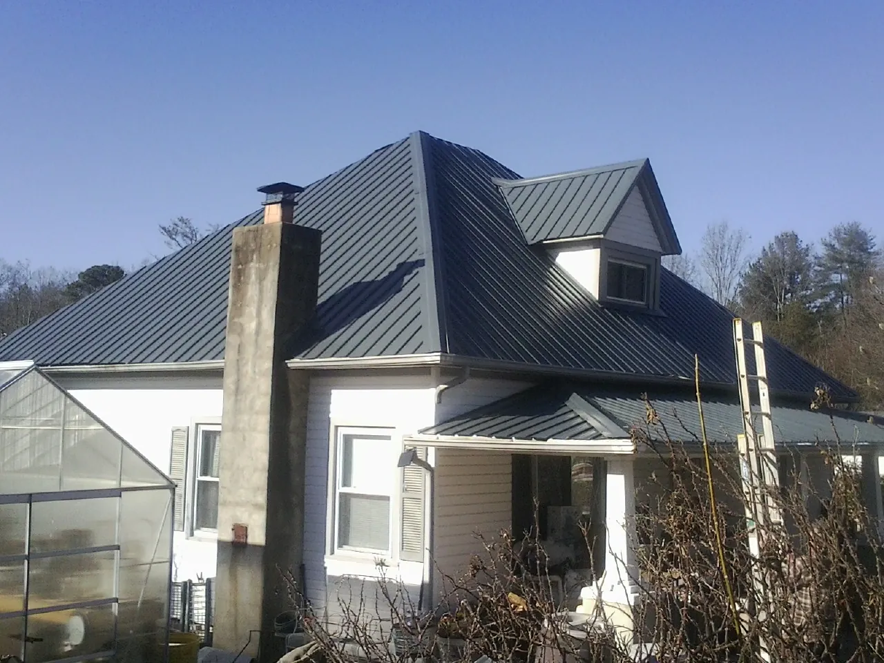 Dark blue standing seam metal roof on a white farmhouse with dormer — Slate & Tile Roof Repair by Roofing Brothers in Markleville