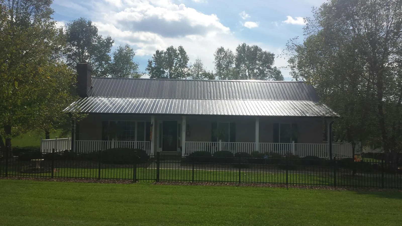 Gray metal roof on a brick ranch with a full width front porch — Gutter Guard Installation work by our crew in Markleville