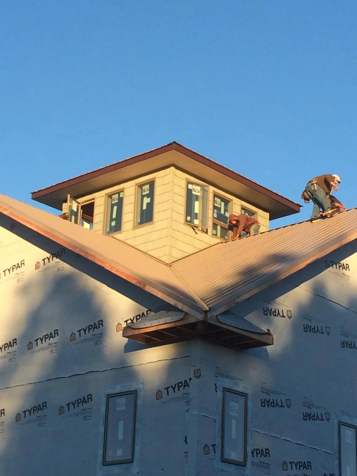 Roofers working around a rooftop cupola on a new metal roof at sunset — Roof Waterproofing in Markleville by Roofing Brothers